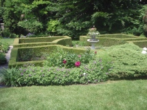 A birdbath filled with plants is the focal point of a formal garden.