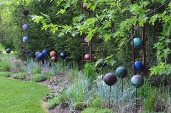 A grouping of spherical sculptures adds shape and colour to a garden.