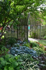 A large trellised archway leads from one garden into another.