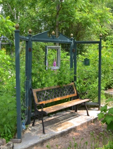 A garden bench is backed by a screen on which sweet peas are growing.